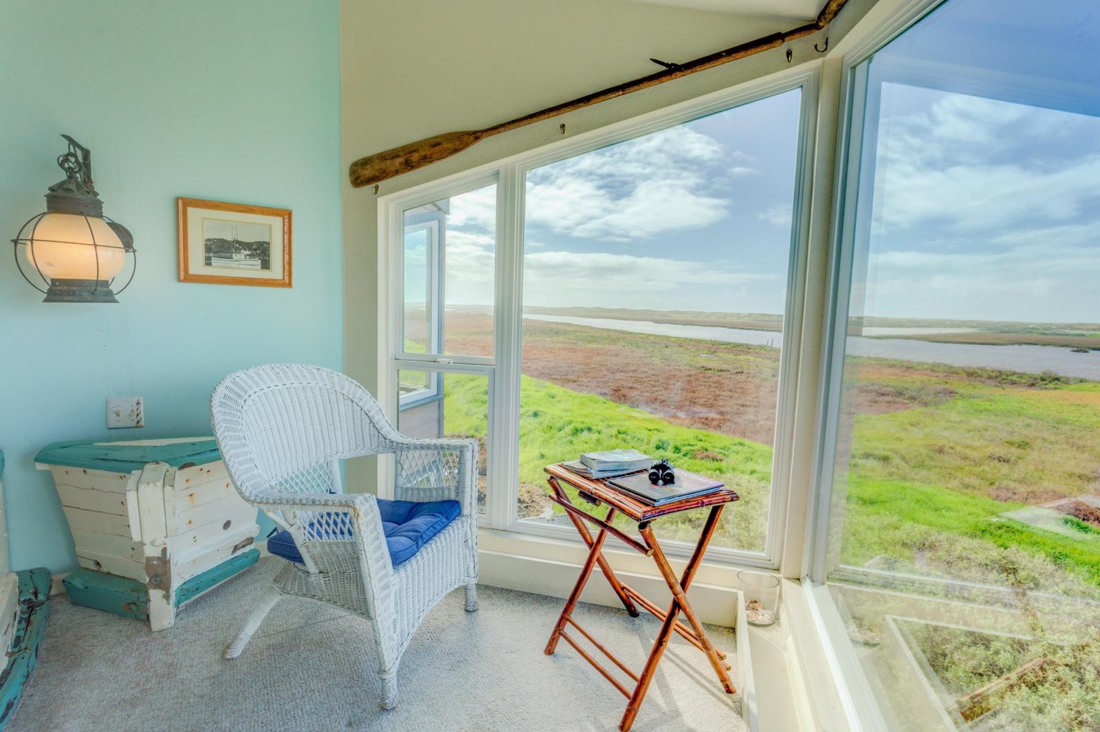 Interior of hotel room at Captain's Inn in Moss Landing. A chair and table seated in front of a large window looking out at the Elkhorn Slough marsh landscape