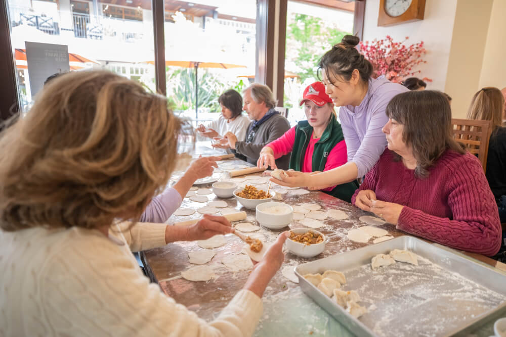 A group of women sat around a table at a restaurant in Carmel-by-the-Sea for a dumpling making workshop for Carmel Culinary Week
