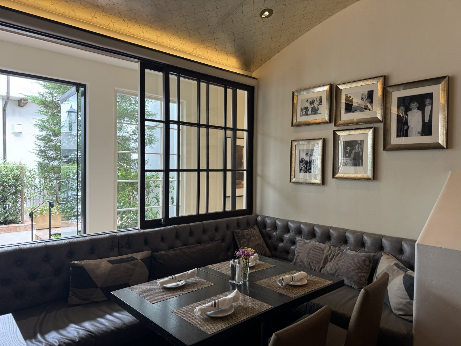 Best Breakfast & Brunch Spots in Monterey County Interior booth seating with big window overlooking patio with trees at Terry's Lounge in Carmel-by-the-Sea