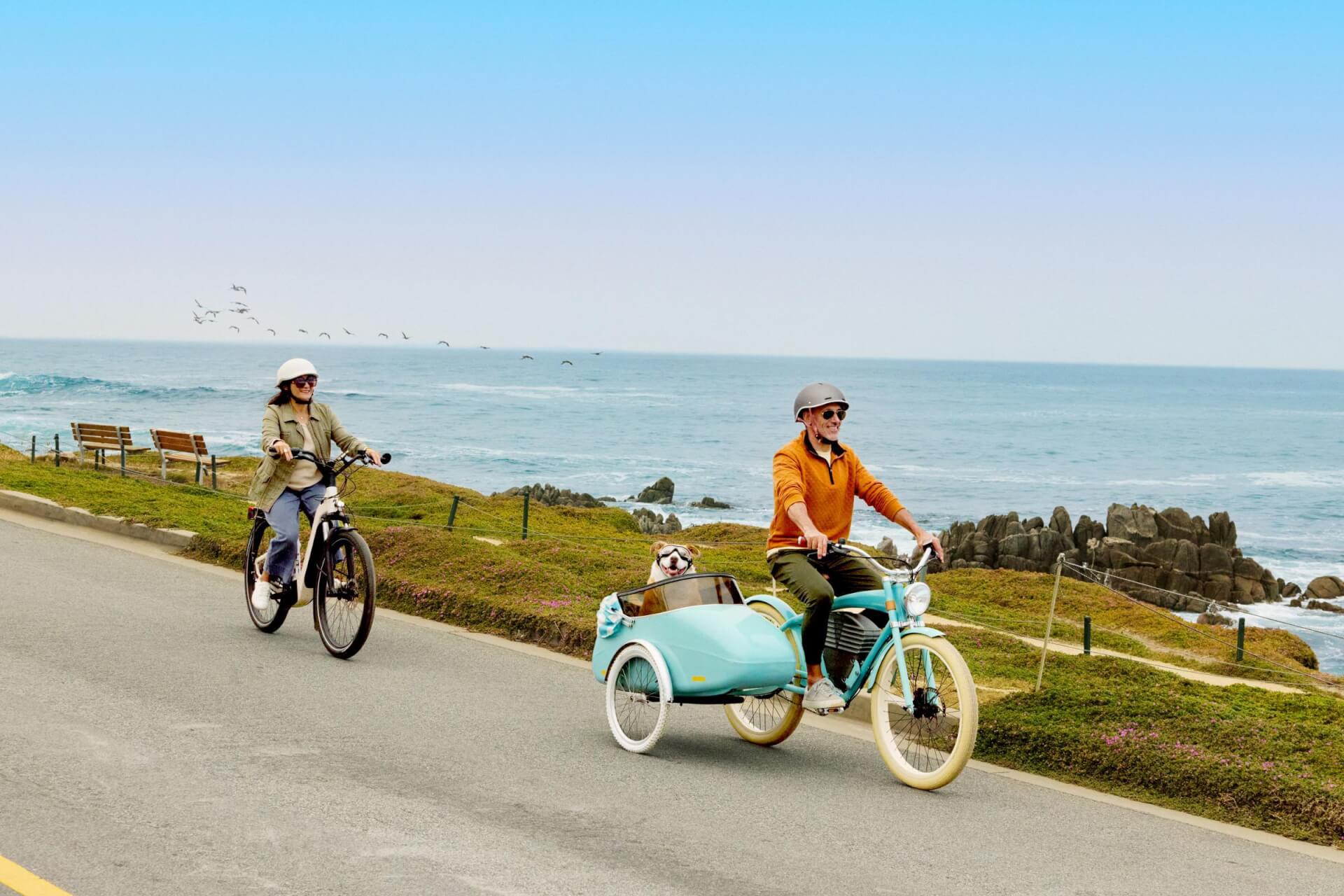 Couple biking with dog along Monterey Bay Coastal Recreation Trail in Pacific Grove, California with electric bikes from Mad Dogs & Englishmen