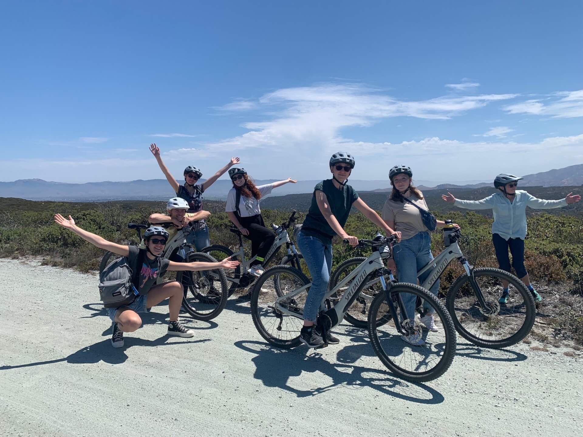 Monterey Biking This is an image of a group of people smiling and posing for the camera on their bikes and helmets at Fort Ord National Monument on a VineCycle Tour